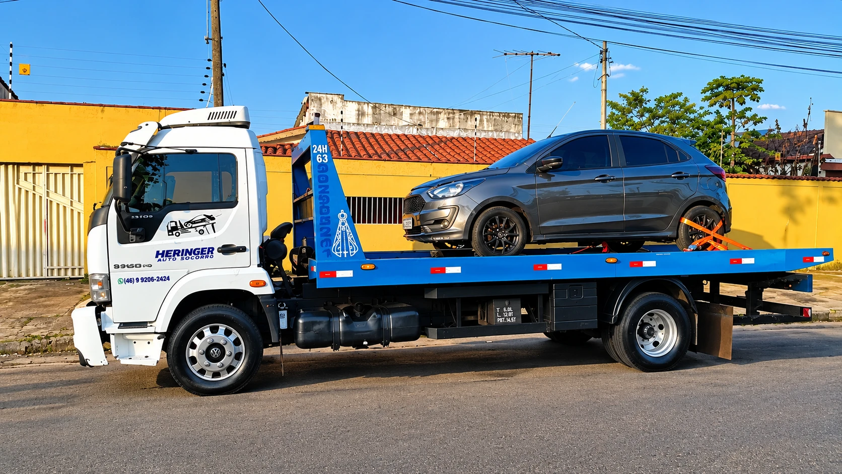 Caminhão guincho plataforma da frota Heringer Auto-Socorro transportando veículo